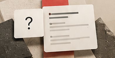 Two cards on stone and red surfaces, one with a question mark and one with lines of answer text